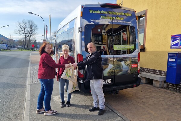 Mitarbeitender der B&auml;ckerei R&auml;the &uuml;berreichen einem Busfahrer des Wanderbuses ein Genusspaket Th&uuml;ringer Meer.
